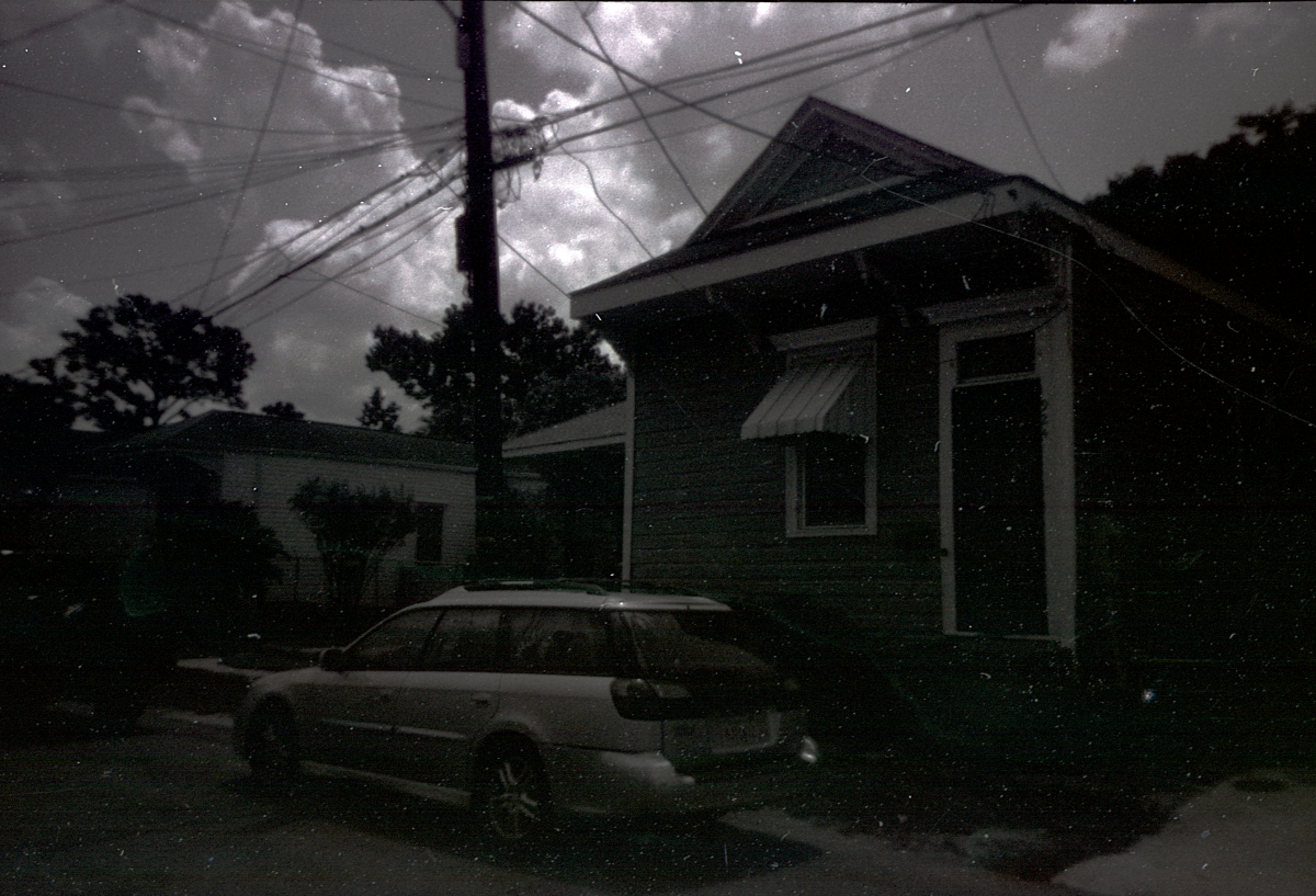black and white photo of a rowhouse with a subaru parked in front