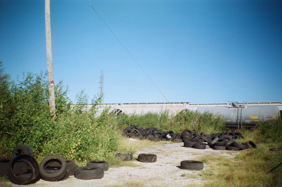 train and overgrown weeds and trashed piles of tires