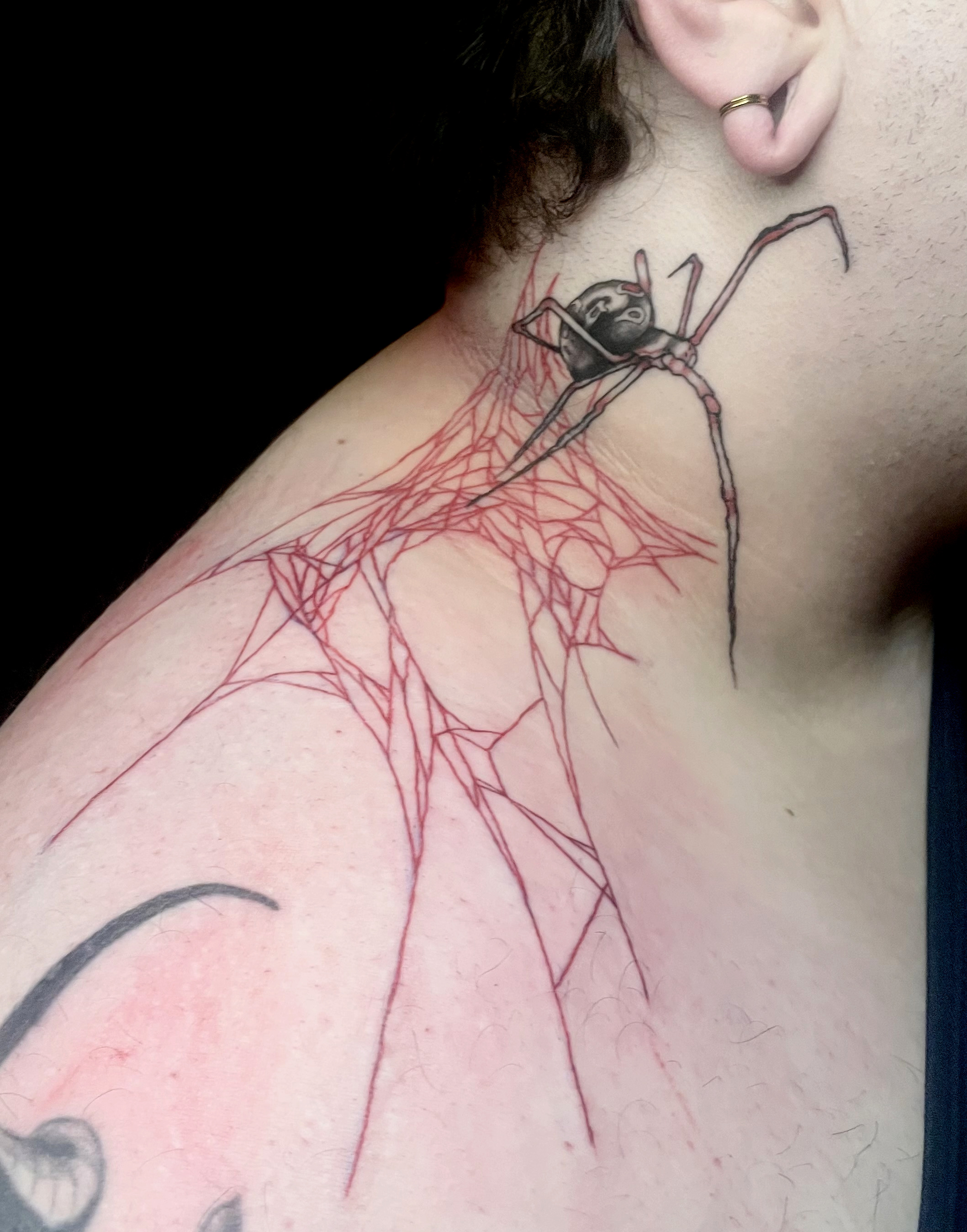 tattoo of a red spiderweb and red widow on neck and shoulder