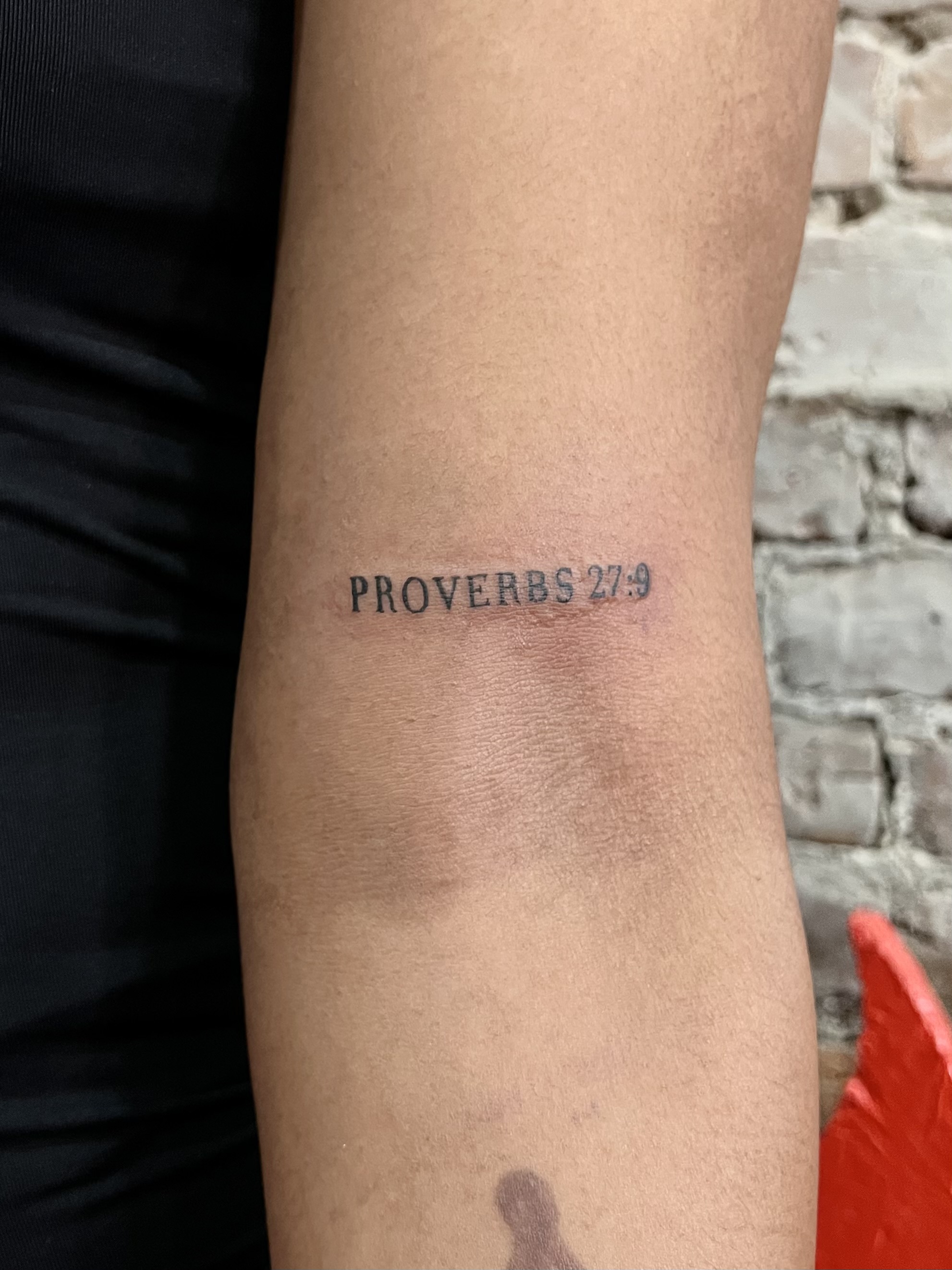 tattoo of text that says proverbs 27:9 on an arm
